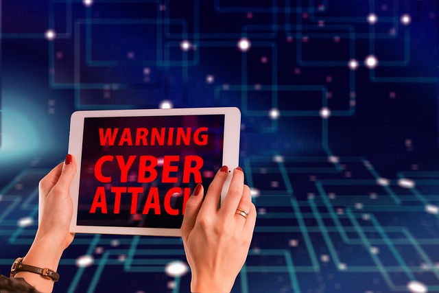 Two hands holding a tablet displaying a 'WARNING: CYBER ATTACK' alert, with a digital network background.