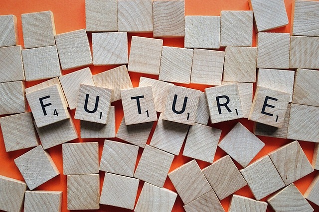 Wooden letter tiles arranged to spell "FUTURE" on a background of scattered blank wooden tiles.