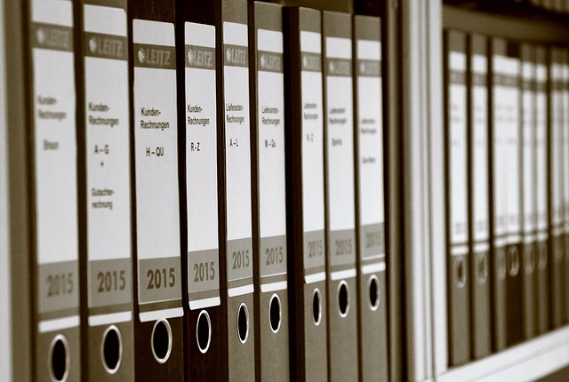 A row of office file binders neatly labeled and arranged on a shelf. 