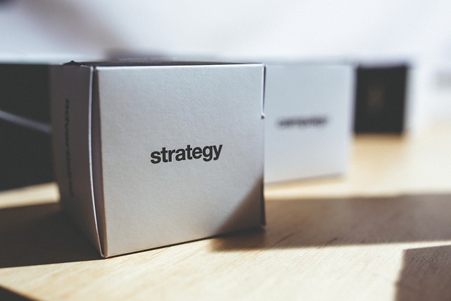 A close-up of a white box on a wooden surface with the word "strategy" printed on it in black letters.