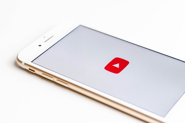 A smartphone displaying YouTube's red play button icon on a white screen.